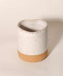 Copo Coração de cerâmica, com a base em argila natural e topo em esmalte branco salpicado, em fundo neutro Esmo