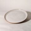 Prato de cerâmica esmaltada branco salpicado com borda em argila tabaco natural e silhueta plana. By Esmo.