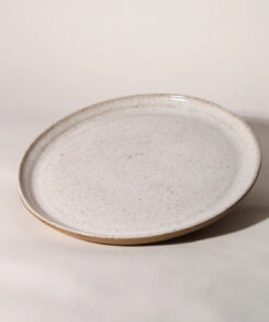 Prato de cerâmica esmaltada branco salpicado com borda em argila tabaco natural e silhueta plana. By Esmo.