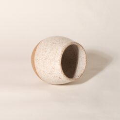 Copo Esmo de cerâmica com design autoral e acabamento em dois tons, argila natural e esmalte branco salpicado, na horizontal.