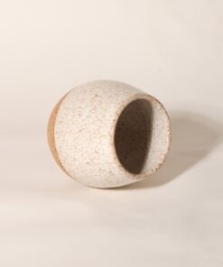 Copo Esmo de cerâmica com design autoral e acabamento em dois tons, argila natural e esmalte branco salpicado, na horizontal.